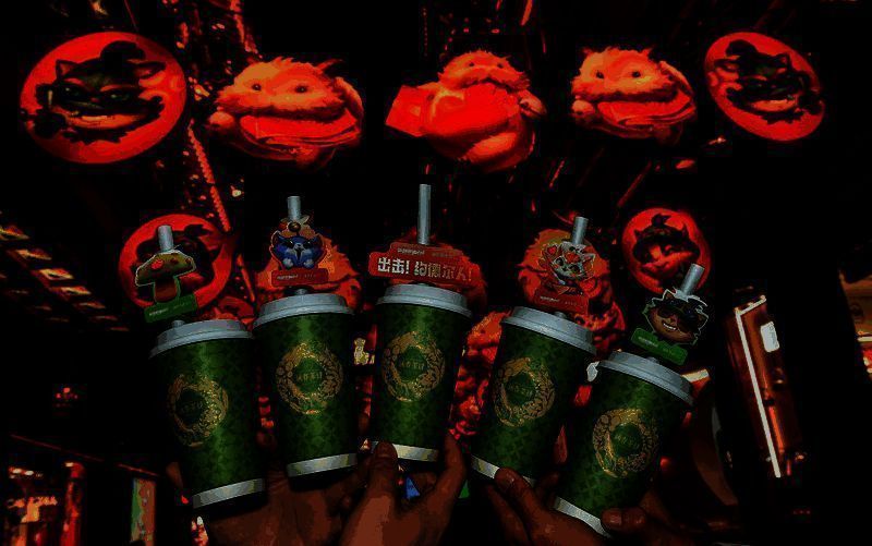 商户店内装饰有《英雄联盟手游》联动海报，顾客正在领取限定周边