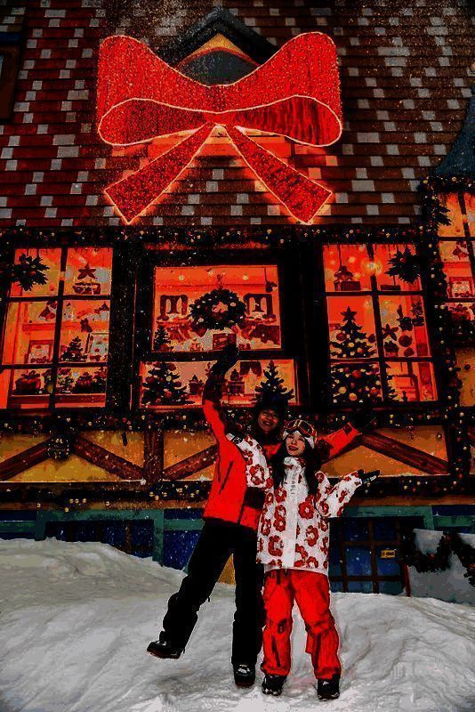 广州热雪奇迹内景,滑雪者在雪道上滑行,背景为灯光装饰的北欧风格木屋与狼人杀角色立牌,空中飘落人造雪花