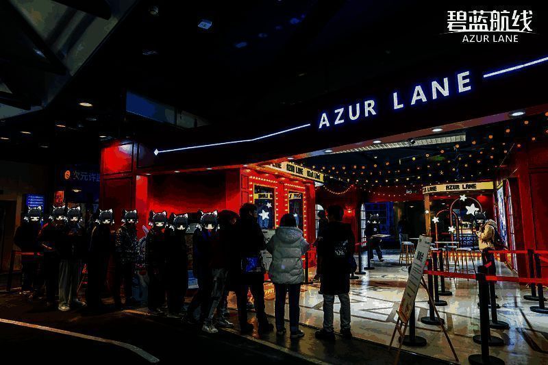 厦门《碧蓝航线》快闪咖啡馆外景，巨型黄鸡坐在屋顶喝咖啡，背景是灯光点缀的童话风格建筑