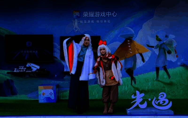 玩家在荣耀游戏中心展区使用手柄游玩《光·遇》,周围观众围观体验