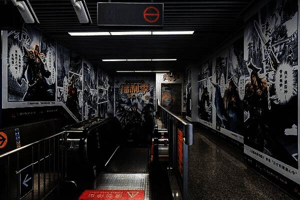 玩家在凤起路地铁站内与《三国杀移动版》角色立牌合影,背景为动态灯箱与游戏台词装饰