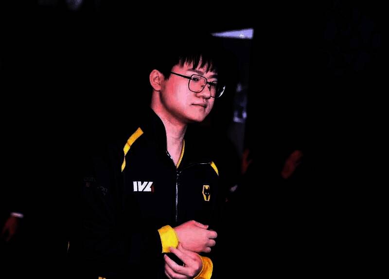 Wolves_Jelly专注比赛中的特写镜头,神情冷静,手握鼠标与键盘,背景为战队LOGO与赛场灯光