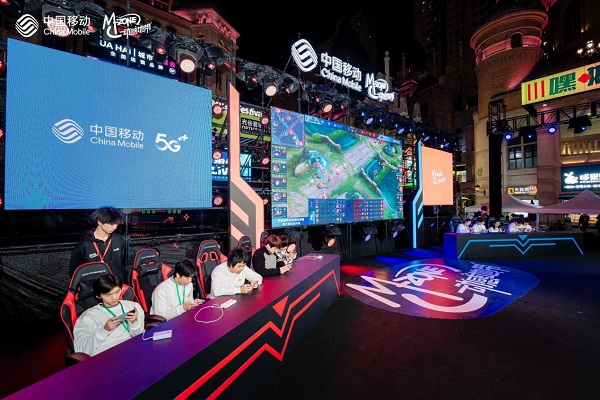 观众在互动区体验5GVR设备，佩戴头显神情投入，周围展台布置充满科技感与潮流元素