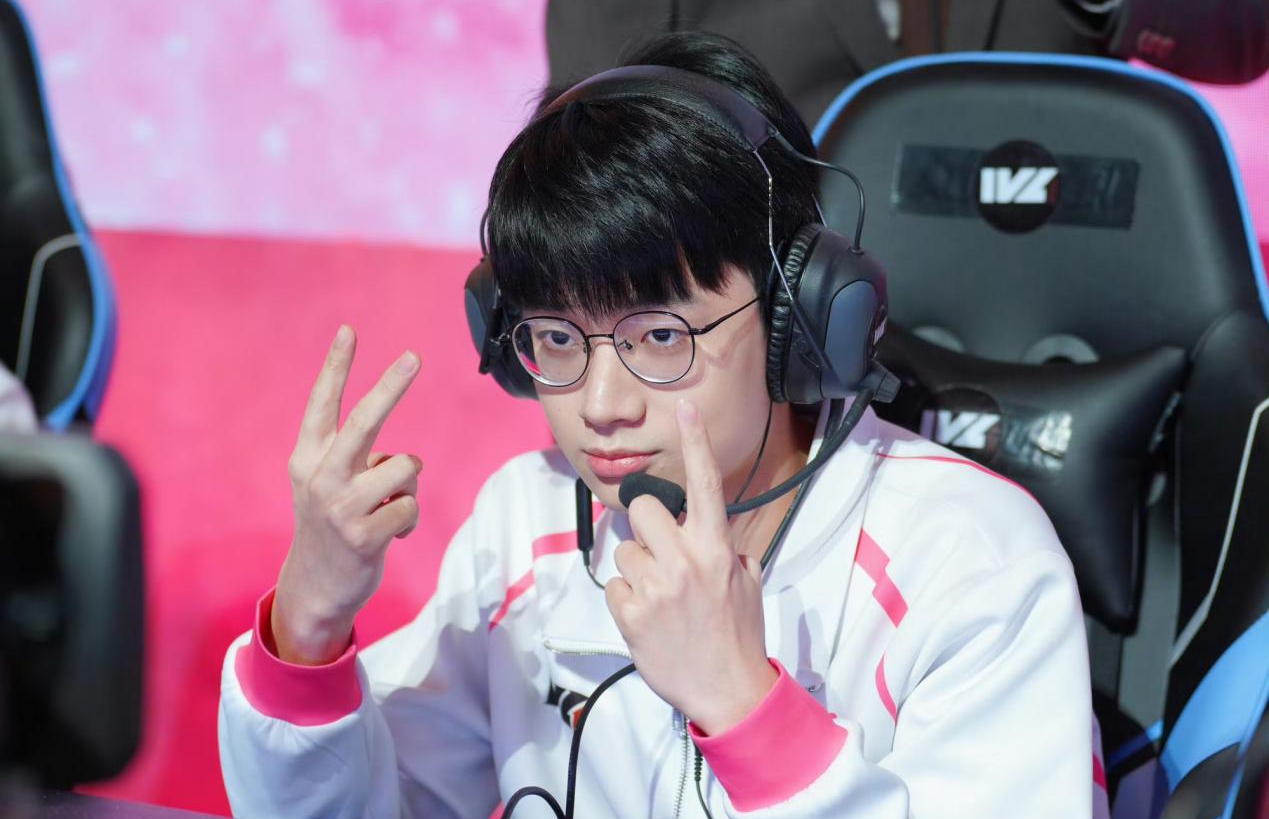 Gr_ac选手特写肖像照，身着Gr战队黑色队服，佩戴耳机直视镜头，背景为电竞舞台灯光与战队LOGO，神情专注而沉稳